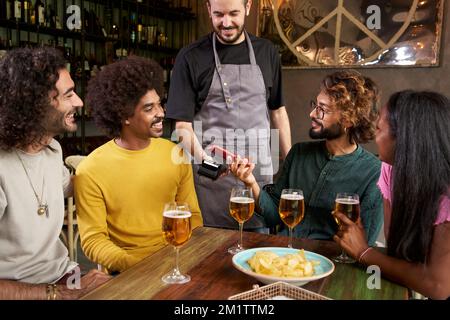 Customer making wireless or contactless payment using smartphone in a bar Stock Photo