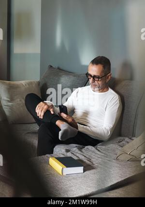 Man on couch with smartphone. Stock Photo