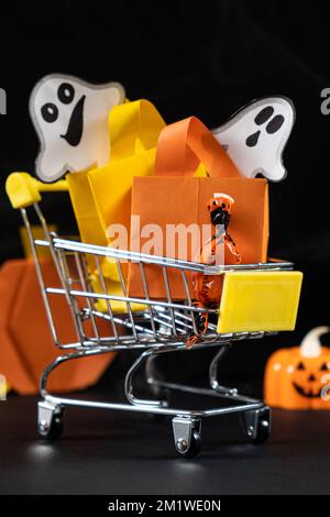 A small cart with bags, gifts on the black background of pumpkins. Halloween Sale Stock Photo