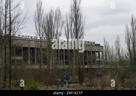 Palace of culture energetik abandonated building in autumn with tourist branched trees and cloudy sky at background Stock Photo