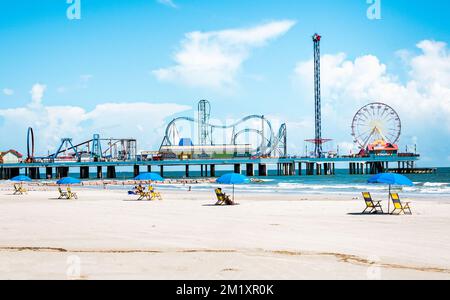 Galveston, TX, US - October 04, 2018: View of beach umbrellas and Pleasure Pier amusement park on Galveston Island Texas. Stock Photo