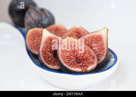 Halves and whole Black Mission figs with focus on the texture of the pulp and seeds placed in a a small ornamental plate, tasty fruit Stock Photo