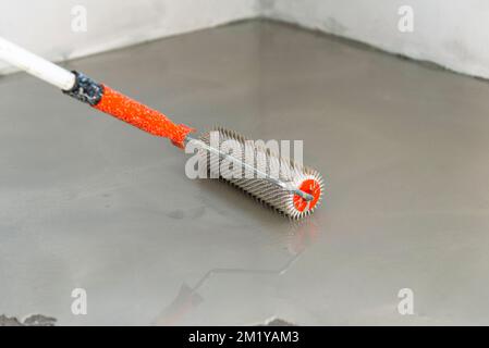 Needle roller for self-leveling floors. Leveling the floors with a cement mixture. Stock Photo