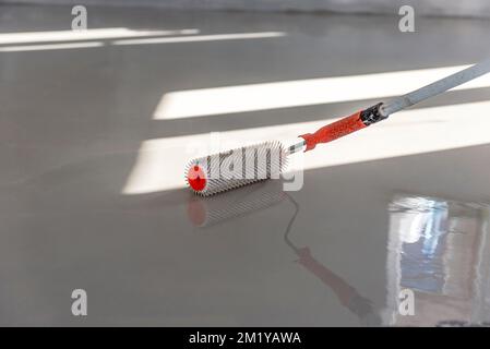 Needle roller for self-leveling floors. Leveling the floors with a cement mixture. Stock Photo