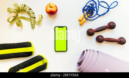 Sports Fitness concepts with Gym equipment. Flat lay of mobile phone with and sport equipment on white table background. Weight control, healthy lifes Stock Photo