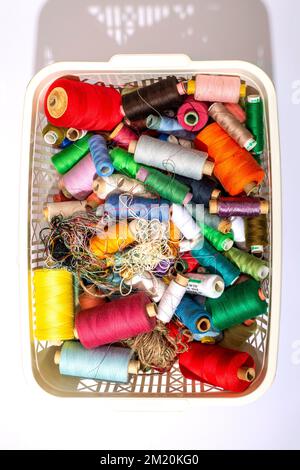 A box with multi colored coins of different threads, top view Stock Photo