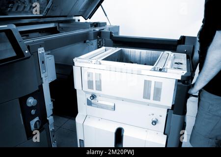 The worker moves the working camera of the 3D printer into the 3D printer. Large industrial 3D printer printing with polyamide powder in a production laboratory. Multi Jet Fusion. Industrial equipment Stock Photo