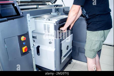 The worker moves the working camera of the 3D printer into the 3D printer. Large industrial 3D printer printing with polyamide powder in a production laboratory. Multi Jet Fusion. Industrial equipment Stock Photo