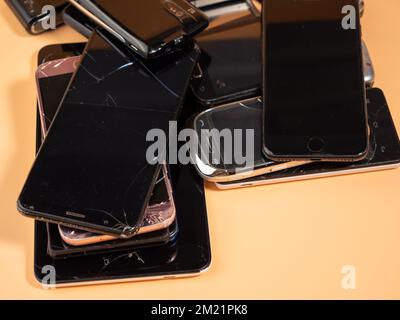 Lots of old smartphones on an orange background. Old mobile phones. Broken smartphones. Stock Photo