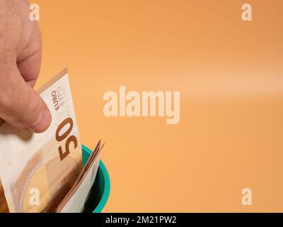 Money in the trash can on an orange background. Euros in the trash. Waste of money concept. Close-up. Stock Photo