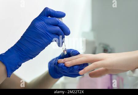 Woman hands in a nail salon receiving a classical manicure - cuticle oil procedure. Hand and nail skin care. Manicure and pedicure procedures and SPA. Stock Photo