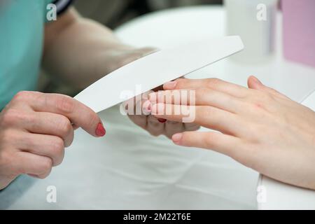 Woman hands in a nail salon receiving a classical manicure - nails filling.  Nail care. Manicure and pedicure procedures and SPA. Close up, selective Stock Photo