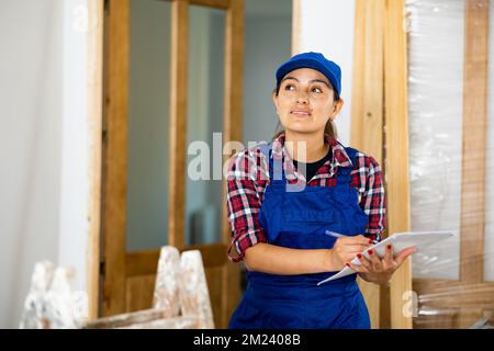 Positive woman builder with documents in apartment Stock Photo