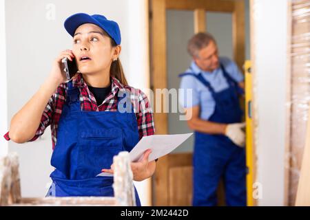 Woman construction manager talking on phone in apartment Stock Photo