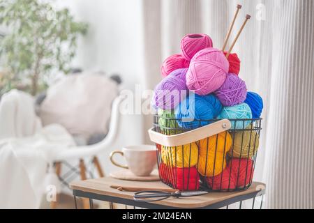 Cozy homely atmosphere. Female hobby knitting. Yarn pastel multicolor in a basket. Stock Photo