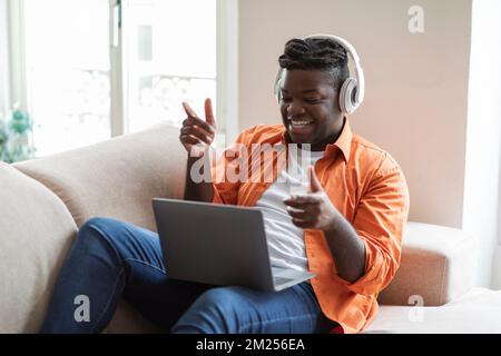 Cool black guy having video call with friends, home interior Stock Photo