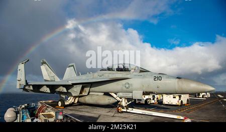 San Diego, United States. 10 December, 2022. A U.S. Navy F/A-18E Super Hornet fighter aircraft, with the Mighty Shrikes of Strike Fighter Squadron 94 parked on the flight deck of the Nimitz-class aircraft carrier USS Nimitz as a rainbow forms above on the Pacific Ocean, December 10, 2022 near California, USA.  Credit: MC2 Justin McTaggart/U.S. Navy/Alamy Live News Stock Photo