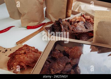 Some craft cardboard boxes with dehydrated dog treats, the highest one is opened, full of dry meat crunchy tastes from beef and chicken. Homemade pet Stock Photo