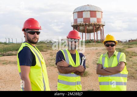 Portrait of three industrial workers standing outdoors with arms crossed. Stock Photo