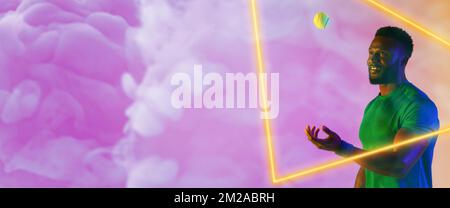 Illuminated triangle over african american male tennis player catching ball over smoky background Stock Photo