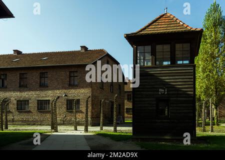 watchtower near to a barrack and double electrical fence barbed wire in nazi Auschwitz concentration camp Stock Photo