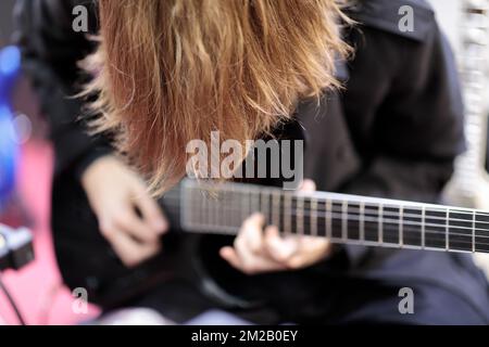 Long hair rock guitarist playing electric guitar. Selective focus. Stock Photo
