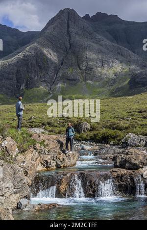 Black Cuillin and tourists visiting the Fairy Pools, succession of waterfalls in Glen Brittle on the Isle of Skye, Scottish Highlands, Scotland, UK | Promeneurs visitent Fairy Pools à Glen Brittle, île de Skye, Ecosse, Royaume-Uni 02/06/2017 Stock Photo