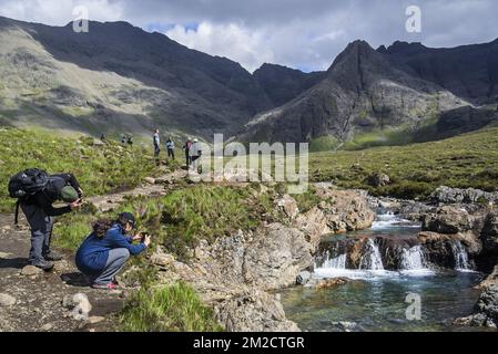 Walkers taking pictures of the Fairy Pools, succession of waterfalls in Glen Brittle on the Isle of Skye, Scottish Highlands, Scotland, UK | Promeneurs visitent Fairy Pools à Glen Brittle, île de Skye, Ecosse, Royaume-Uni 02/06/2017 Stock Photo