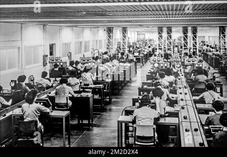 Old black and white archival photograph showing female workers manufacturing small electric motors in factory in the 1950s | Vieille photo des femmes assemblant des moteurs électriques dans usine pendant les années cinquante 11/02/2018 Stock Photo