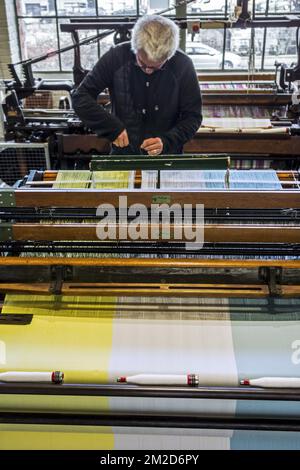 Fabric weaver operating mechanical flying shuttle loom / shuttle weaving machine in cotton mill / spinning-mill | Métier à tisser mécanique dans filature cotonnière 11/02/2018 Stock Photo