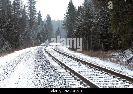 A curved section of BNSF Railroad train tracks in the snow, south of Troy, Montana, on a cold winter morning. Stock Photo