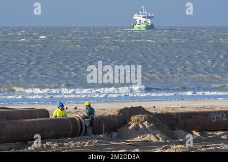 Dredging workers connecting pipes of pipeline during sand replenishment / beach nourishment works along the Belgian coast at Ostend, Belgium | Construction de pipeline par ouvriers de Jan De Nul pour sable de reconstitution sur la plage d'Ostende, Belgique 22/02/2018 Stock Photo