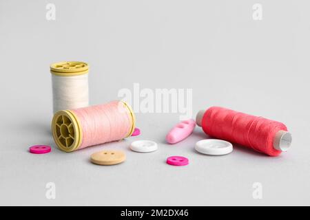 Thread spools and different buttons on grey background Stock Photo