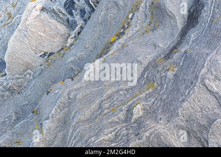 Close-up of a strange and beautiful rock surface with yellow lichen, side view. Abstract full frame natural textured background. Stock Photo