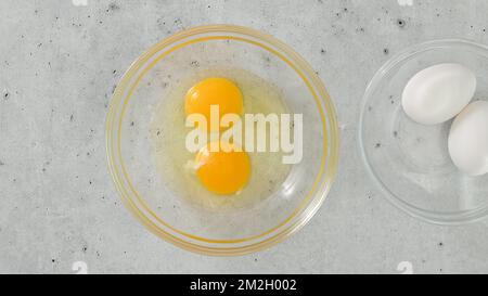 Raw eggs in a glass bowls, close-up on a light grey background, copy space Stock Photo