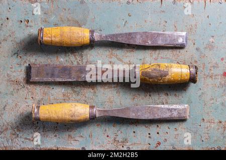 Rotterdam, Netherlands - 11-11-2022: : Three vintage chisels with wooden handels flat lay on a rustic surface Stock Photo
