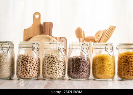 Kitchen jars to store vegetables and pasta next to some cutting boards and some kitchen utensils. Stock Photo