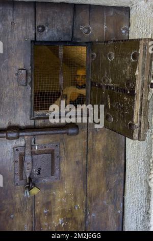 Heavy wooden medieval prison cell door with open hatch showing prisoner ...