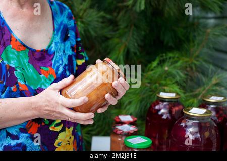 Elderly woman holds jar of homemade conserved jam in her hands Stock Photo