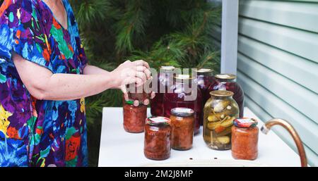 Close up of woman closing lid on jar of homemade canning jam Stock Photo