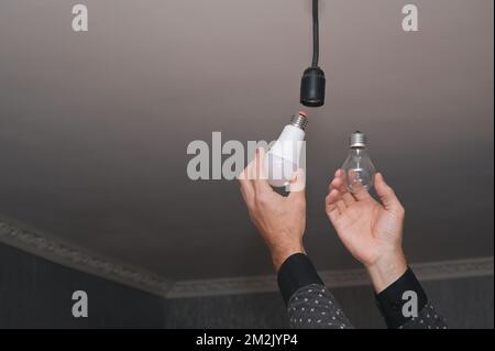 The concept of energy saving. incandescent lamp and energy-efficient LED lamp in your hands. Stock Photo