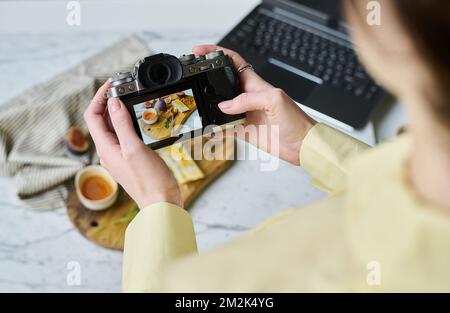 Close-up of woman taking photo of food on wooden board using her professional camera Stock Photo