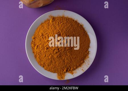 photo of turmeric in a bowl as seen from above on a purple background Stock Photo