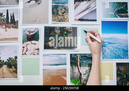 High angle view of photographer making notes on paper on the wall among professional photos Stock Photo