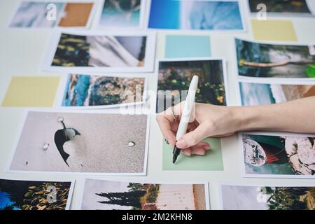 Close-up of photographer making notes on sticky note among professional photos Stock Photo