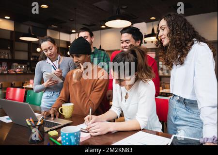 Multiracial mixed group of young people sitting at desk. Co-workers or teamwork of university students working together. Stock Photo