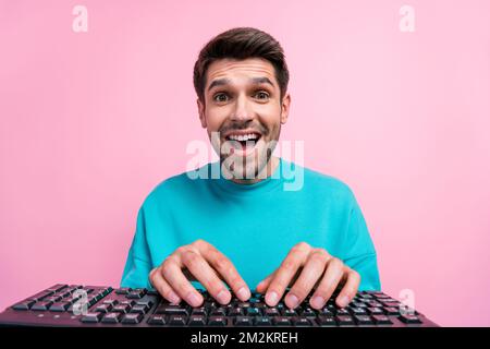 Photo portrait of nice young guy excited typing working keyboard computer wear trendy blue garment isolated on pink color background Stock Photo