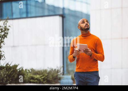 Man holding a digital tablet looking up in the sky Stock Photo