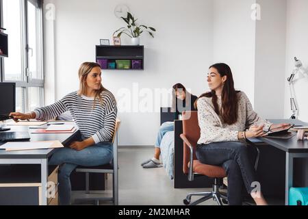 Group of three friends, roommates, studying in the dorm room together Stock Photo