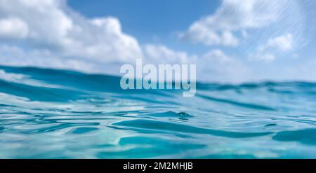 Ocean water background. Soft ripples and waves under beautiful cloudy sky. Tranquil nature sea view, closeup of water surface with horizon surface Stock Photo